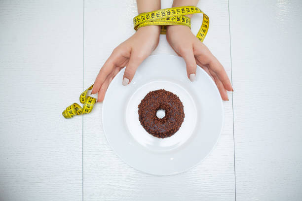 Diet. The concept of healthy and unhealthy nutrition. The model plus size makes a choice in favor of healthy food and fruit by refusing fast food