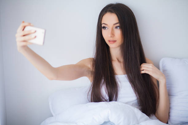 istock Relaxing On Bed During Weekend. Beautiful Woman Relaxing on a Bed and Looking Happy 1150262521