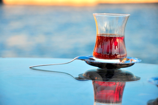half full glass of tea on glass table with its reflection
