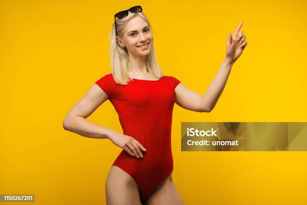 Pretty Blond Lifeguard In Red Swimsuit And Sunglasses Points Finger Up Stock Photo - Download Image Now
