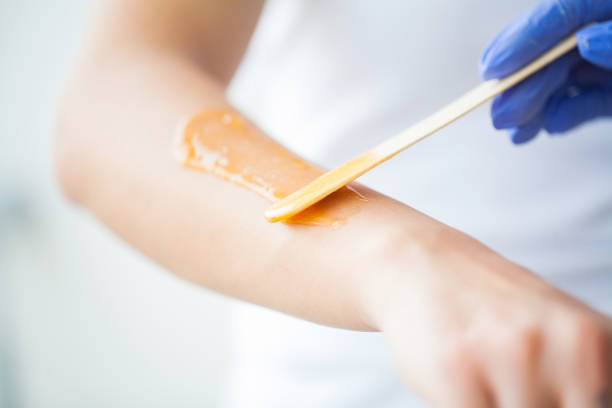 maître ne épilation des mains avec l’aide de la cire chaude de pâte de sucre dans la beauté de salon - épilation à la cire photos et images de collection