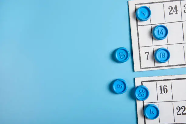 Bingo balls and cards on blue background with copy space.