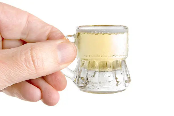 Hand holding a small mug of beer.