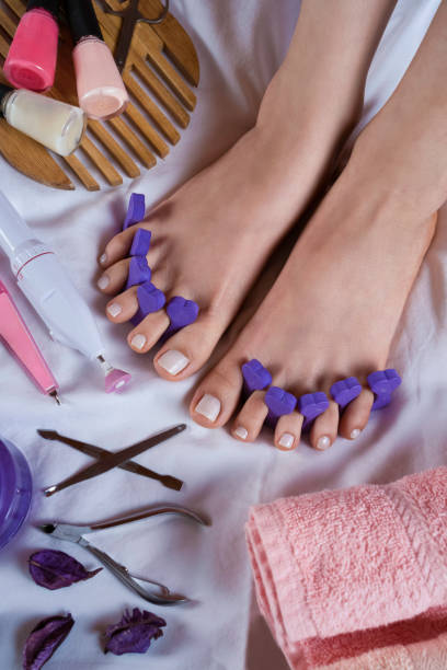 istock Applying pedicure to woman's feet with white toenails, with toe separators 1150274189