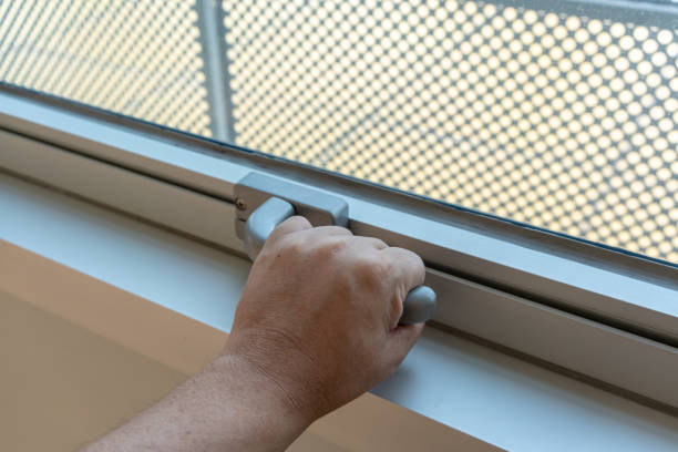 istock Hand holding glass window latch handle. Window lock handle in grey color with two screw bolt on white wall. 1150275621