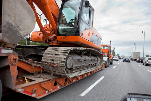 Rear View Of Professional Driver Operating Backhoe