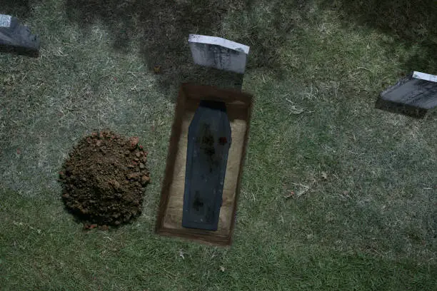 Aerial view of a freshly dug grave site on a haunted Halloween night.  The grave has been freshly dug with pile of dirt and casket.