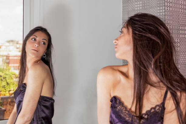 istock young woman looking at herself in a mirror 1150284972