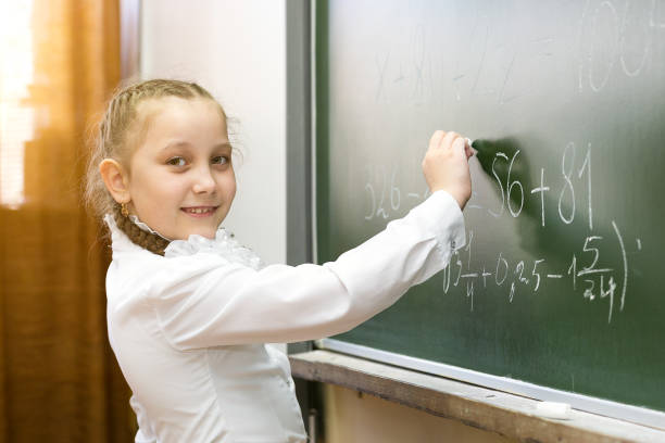 istock A girl female elementary school student writes on the blackboard. 1150285865
