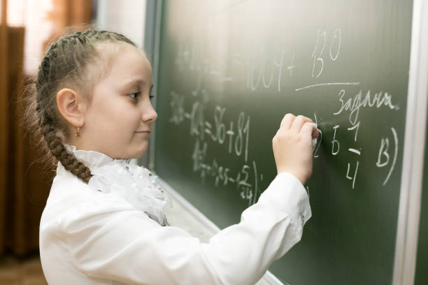 istock A girl female elementary school student writes on the blackboard. 1150285880