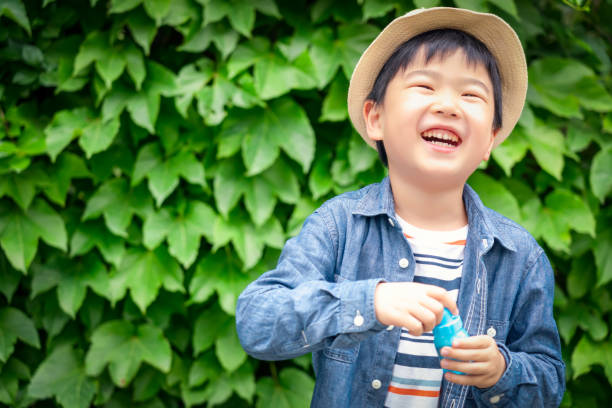 Happy and excited young boy  sitting crossed legged against tree trunk in park wearing casual clothes - with copy space