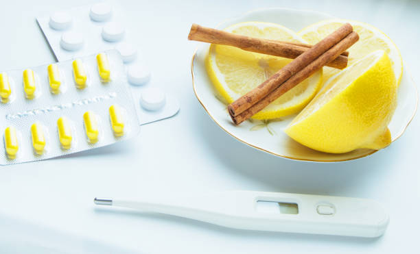 Thermometer, lemon, cinnamon, and tablets - the treatment of colds stock photo