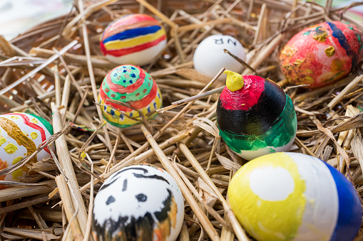 Painted Easter eggs in a basket with straw.