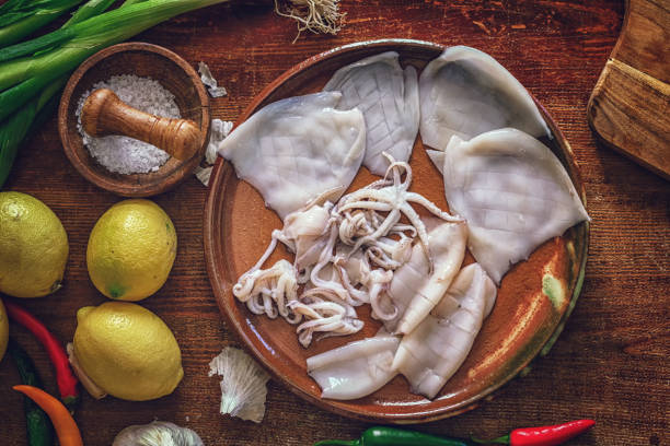 Cleaning and Cutting Fresh Squid on a Wooden Cutting Board
