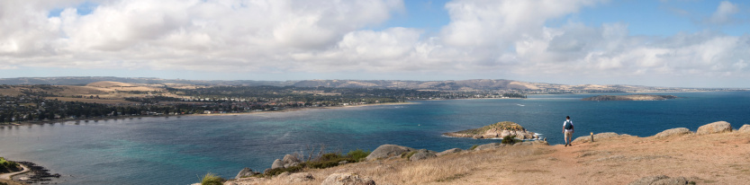 Panorama showing the view from the Bluff, overlooking Encounter Bay and Victor Harbor, rear view of bushwalker in the foreground.