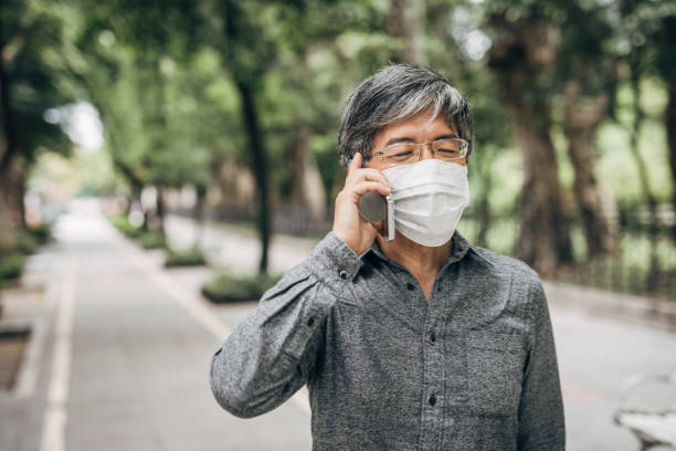 istock Man wearing a face mask and using phone 1150307127