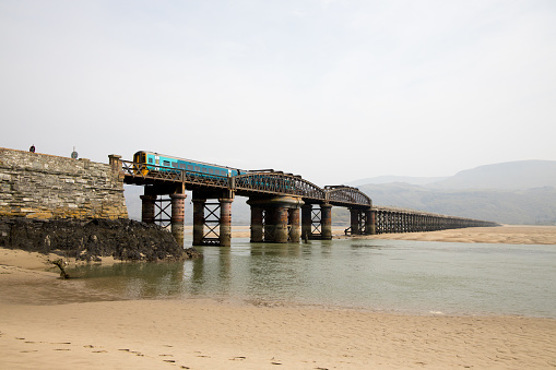 Transport for Wales Train passing the beach at Barmouth no people can be seen the tide is out