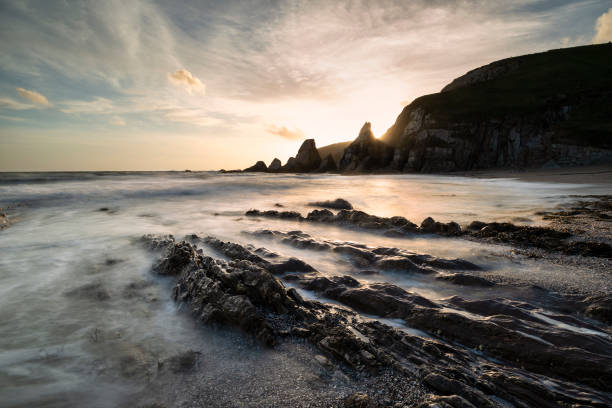 istock Stunning sunset landscape image of Westcombe Beach in Devon England with jagged rocks on beach and stunning cloud formations 1150311020