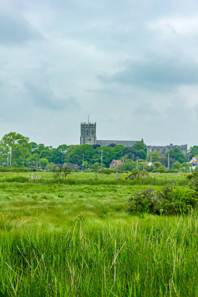 A view of the Christchurch (UK) priory with green vegetation and trees under a cloudy sky A view of the Christchurch (UK) priory with green vegetation and trees under a cloudy sky christchurch england photos stock pictures, royalty-free photos & images