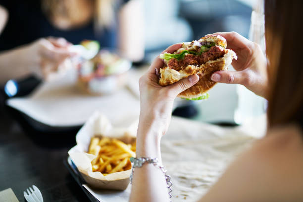 mulher comendo comendo hambúrguer sem carne vegan no restaurante - comida rápida - fotografias e filmes do acervo