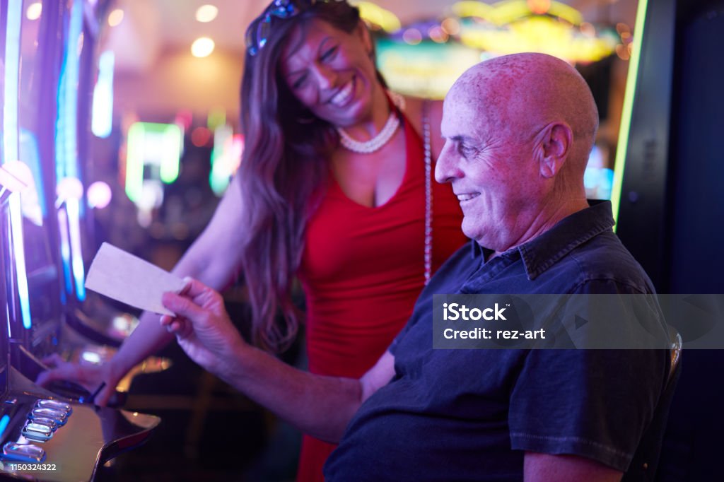 happy mature couple with payout ticket at casino happy mature couple with payout ticket at casino with colorful lights Casino Stock Photo