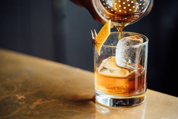 カクテルバーで琥珀色のウイスキーやブランデーアルコール飲料と氷とのクローズアップガラス - brandy snifter ストックフォトと画像