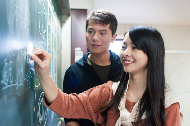 istock Female student explaining a lesson in front the chalkboard to her classmate 1150326480