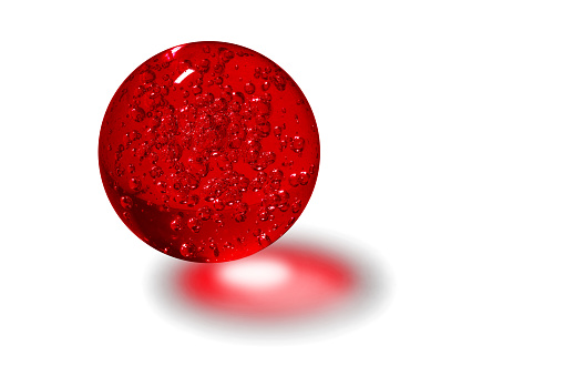 Red glass ball with bubbles inside lit by light with a white background