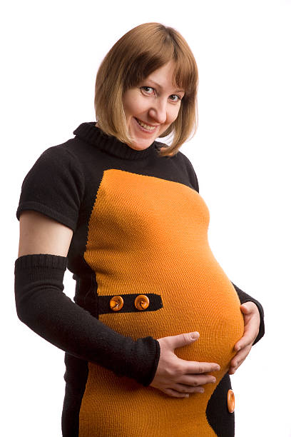 Smiling pregnant women Smiling pregnant women (not model),dressed in funny dress , is holding her belly.XL size photo 8 months pregnant stock pictures, royalty-free photos & images