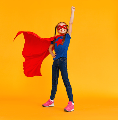 the concept of child superhero costume on yellow background