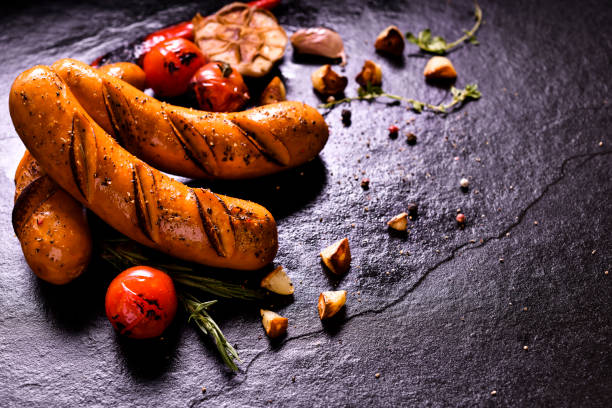 istock Grilled sausages and various vegetables on black stone background 1150334697