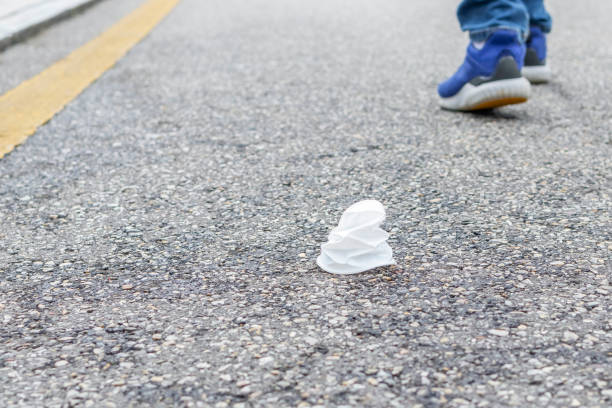 istock Crumpled white plastic cup on an asphalt road with a yellow stripe 1150335362