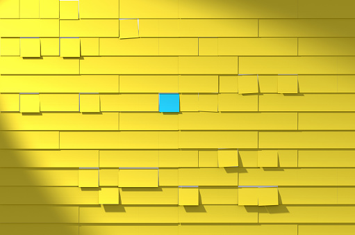 Wall full of yellow sticky notes with one blue note in the middle