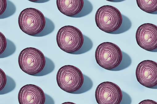 Half sliced red Spanish onion in a row on blue background