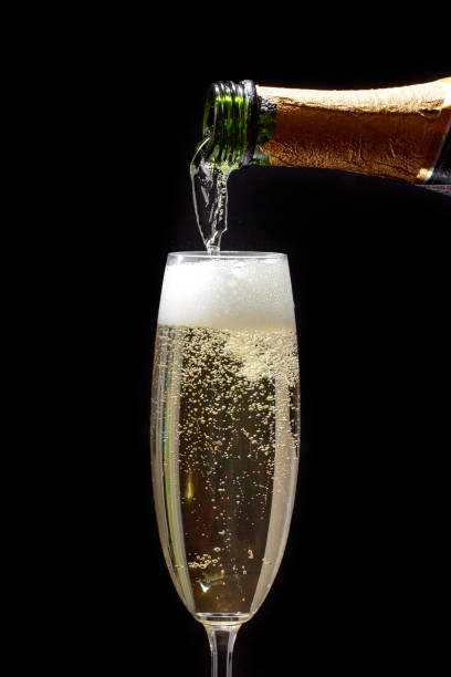 champagne étant versé dans un verre sur un fond noir - champagne pouring champagne flute glass photos et images de collection