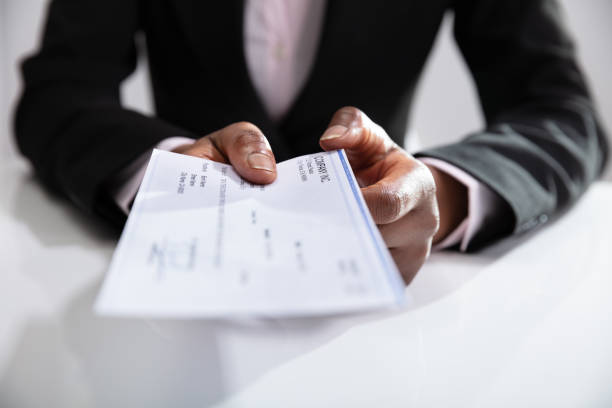 istock Businesswoman's Hand Giving Cheque 1150345115