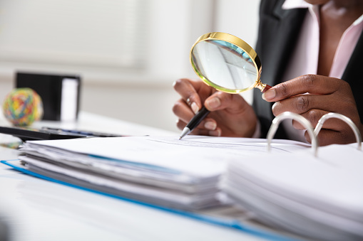 Photo Of Businessperson Examining Bill Through Magnifying Glass