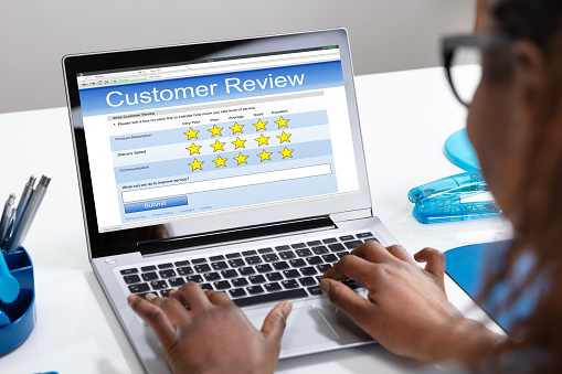 Close-up Of A Businesswoman's Hand Filling Customer Review Form On Laptop Screen