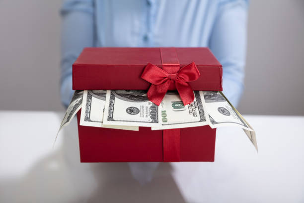 istock Female's Hand Holding Gift Box Filled With Currency 1150345246