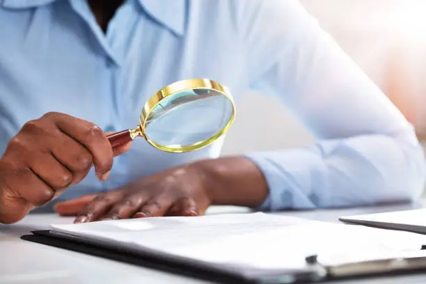 Photo of Businessperson Looking At Contract Form Through Magnifying Glass