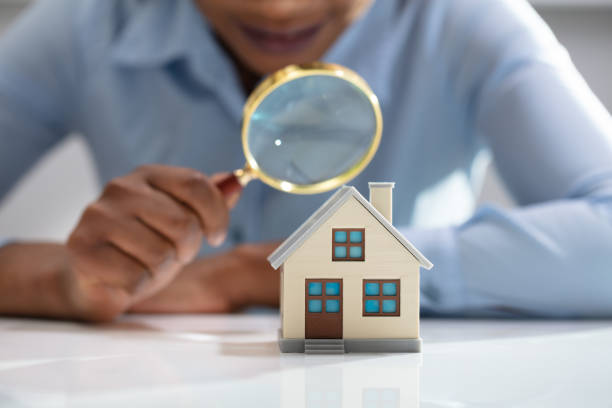 businesswoman holding magnifying glass over house model - home inspection imagens e fotografias de stock