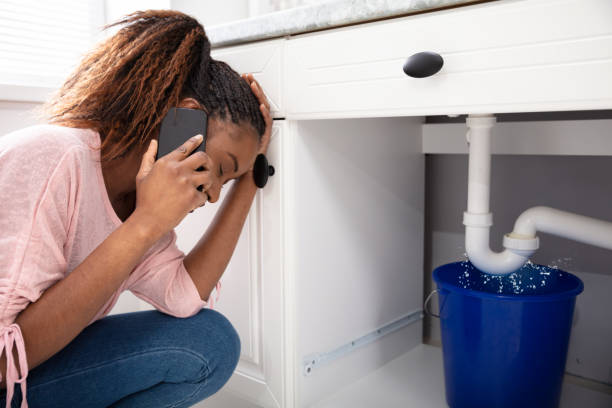 istock Woman Calling Plumber In Front Of Leaking Sink Pipe 1150345506