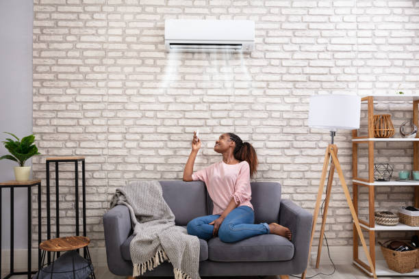 istock Woman Operating Air Conditioner With Remote Control 1150345556