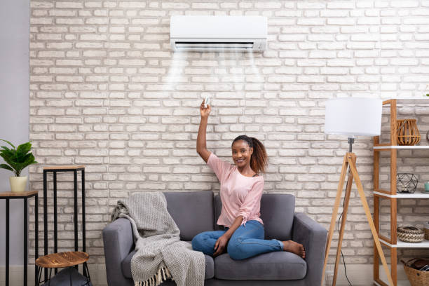istock Woman Operating Air Conditioner With Remote Control 1150345559
