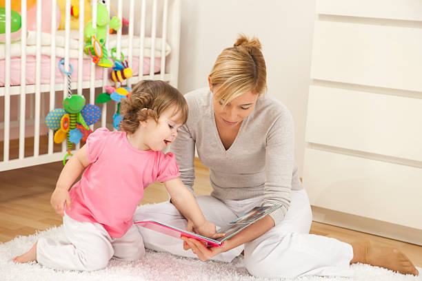 A mother reading a story book to her baby girl stock photo