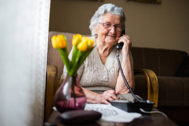 거실에서 전화로 이야기하는 행복한 선배 여성. - landline phone 뉴스 사진 이미지