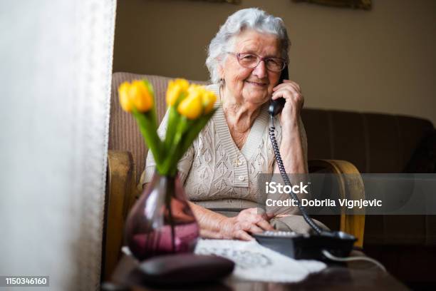 Happy Senior Woman Talking On The Phone In Living Room Stock Photo - Download Image Now