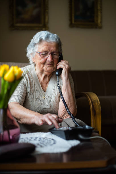 starsza kobieta przez telefon - senior adult independence lifestyles home interior zdjęcia i obrazy z banku zdjęć