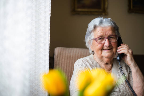 Portrait of an older woman talking with the phone. Old senior woman having a cheerful conversation over her phone, talking with a friend or a relative . only senior women stock pictures, royalty-free photos & images