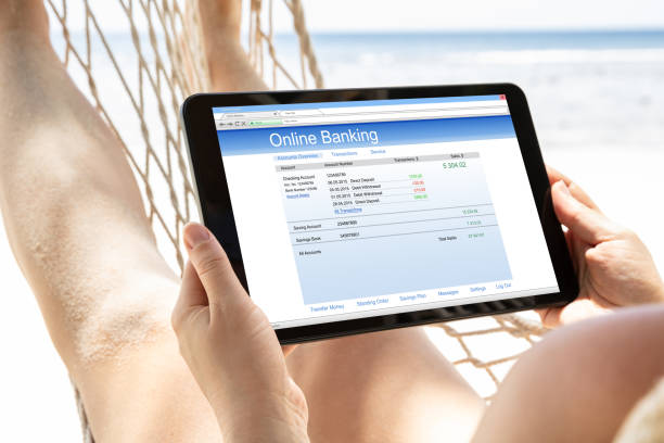 Woman Lying On Hammock Using Online Banking On Digital Tablet